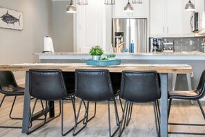 A modern kitchen with a central island, black chairs, and pendant lighting.
