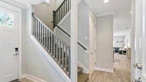 Un interior moderno con una escalera, una puerta y vistas a un salón.