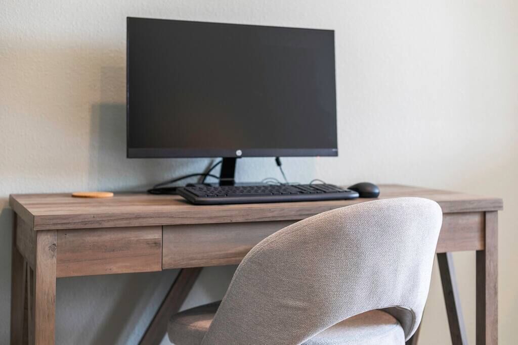 Ein Holztisch mit Computerbildschirm, Tastatur und Maus.