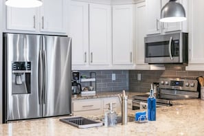Eine moderne Küche mit Edelstahlgeräten, weißen Schränken und Granit Arbeitsplatten.