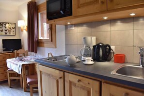 A compact kitchen with wooden cabinets, a microwave, a coffee maker, and a sink. - 300m from shops, 2nd floor, balcony, tv, ski locker, 18m ², Méribel (Méribel - Les Allues)