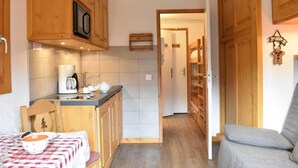 Een compacte keuken met houten kastjes, een koffiezetapparaat en een tafel met een geruit tafelkleed.