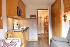 A compact kitchen with wooden cabinets, a coffee maker, and a table with a checkered tablecloth. - 300m from shops, 2nd floor, balcony, tv, ski locker, 18m², Méribel (Méribel - Les Allues)