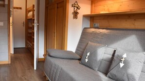 Een gezellige kamer met een grijze bank, een houten garderobe en een decoratie aan de muur.