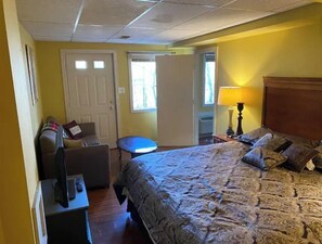 A hotel room with a bed, a desk with a computer, a chair, and a small table.