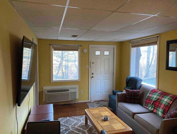 A living room with a sofa, a coffee table, a TV, and a door.