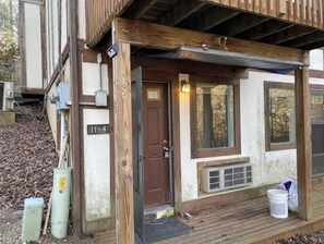 A wooden cabin with a front door, a small porch, and a window.