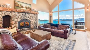 Un amplio salón con chimenea de piedra, sofás de cuero y grandes ventanales con vistas al lago.