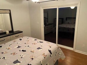 A bedroom with a bed, dresser, and sliding glass door leading to a balcony.