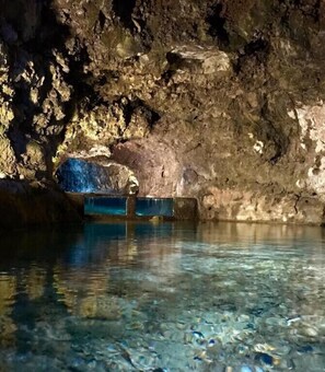 A cave with clear water and a blue object in the center.