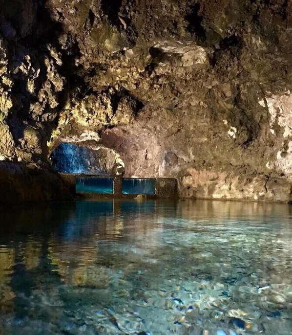En grotta med klart vatten och ett blått föremål i mitten.
