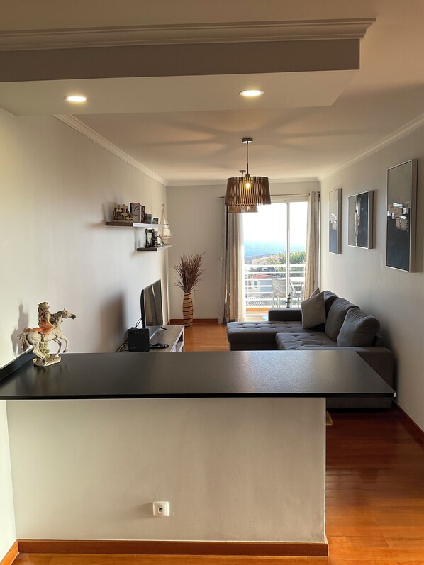 A modern living room with a sofa, a dining area, and a view of the outdoors. - Sol & Mer Ranch (Câmara de Lobos)