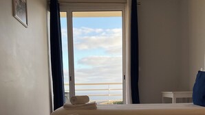 Ett hotellrum med två sängar, havsutsikt och ett litet bord.