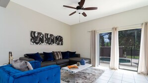 A modern living room with a sectional sofa, a coffee table, and abstract wall art. - Cozy 3 bedroom home with Private Pool 4564 (Kissimmee)