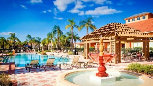 A resort pool area with lounge chairs, a gazebo, and palm trees. - Cozy 3 bedroom home with Private Pool 4564 (Kissimmee)