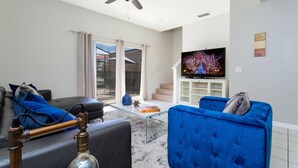 A living room with a sofa, a blue armchair, a television, and a hookah. - Cozy 3 bedroom home with Private Pool 4564 (Kissimmee)