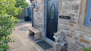 Un edificio de piedra con una puerta negra que dice "The Keep", un banco de piedra, una gárgola de piedra y un muro de piedra.