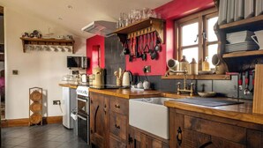 Una cocina con armarios de madera, microondas, estufa y lavabo.