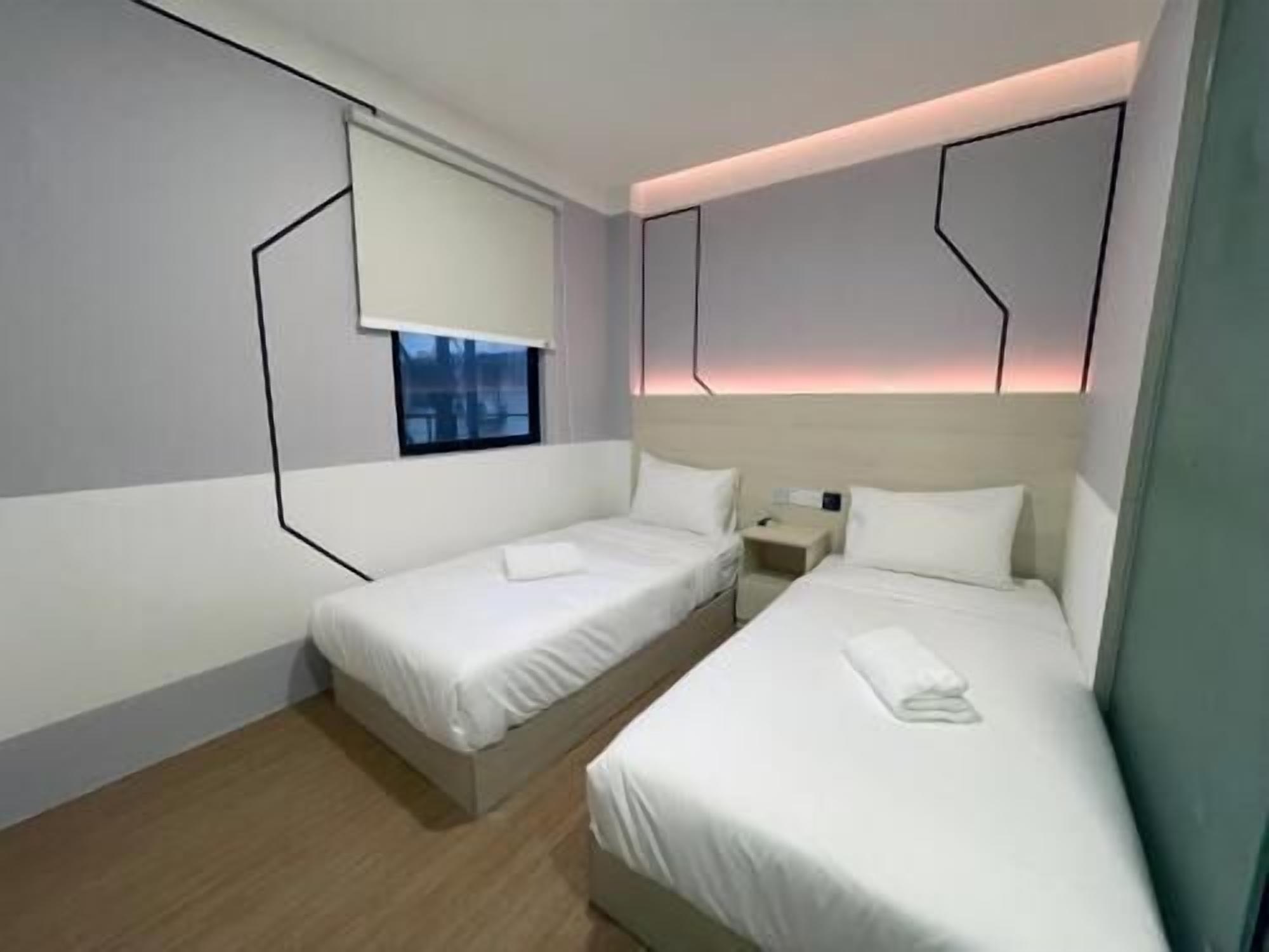A hotel room with two beds, a window, and a nightstand.