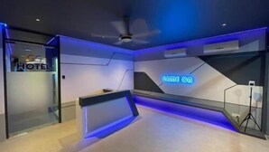 Habitación de hotel moderna con mostrador de recepción, un letrero de neón y un ventilador de techo.