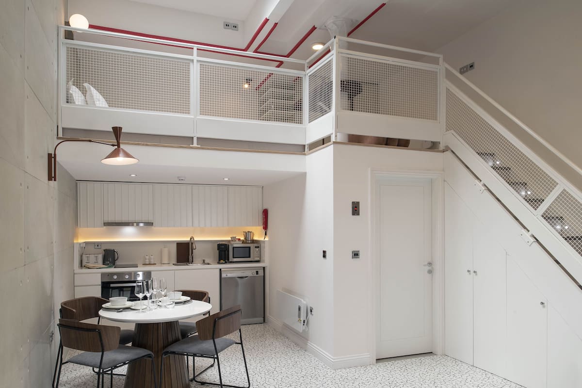 A modern kitchen with a dining area, a staircase, and a skylight.