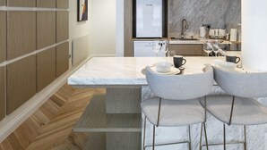 A modern kitchen with a marble countertop, wooden cabinetry, and a built-in bar area with bar stools. - Trueman Court Luxury Serviced Apartments (Liverpool)