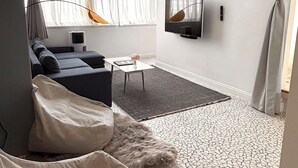 A modern living room with a sofa, a coffee table, a TV, and a patterned floor. - Trueman Court Luxury Serviced Apartments (Liverpool)