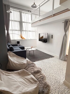 A modern living room with a sofa, a coffee table, a TV, and a patterned floor.