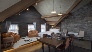 A modern loft bedroom with a sloped ceiling, exposed beams, and a stone wall. - Trueman Court Luxury Serviced Apartments (Liverpool)