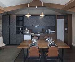 Una cucina moderna con mobili scuri, un tavolo da pranzo in legno apparecchiato per sei persone e un forno a incasso.