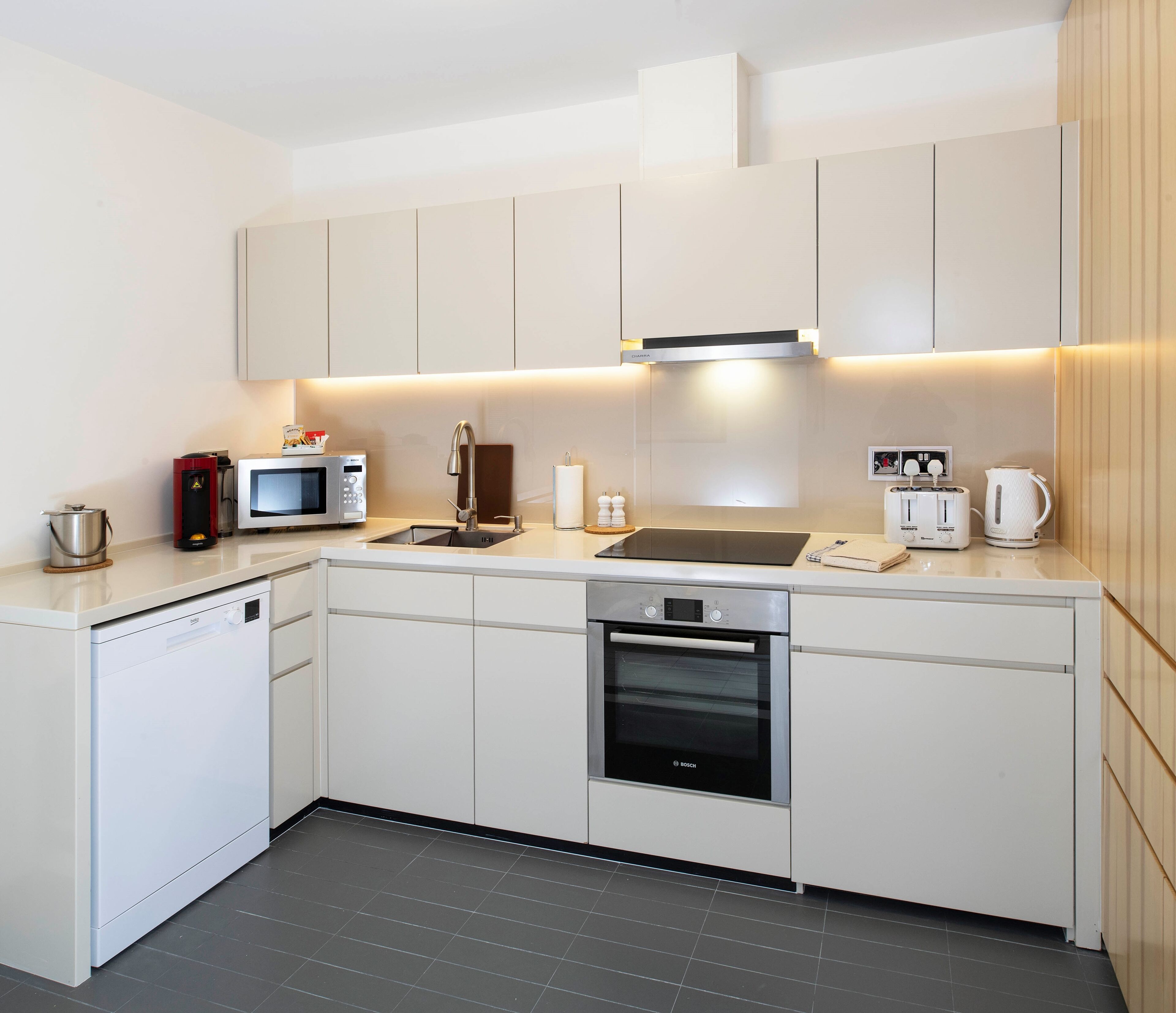 A modern kitchen with white cabinetry, a Bosch oven, a microwave, a coffee maker, and a toaster.