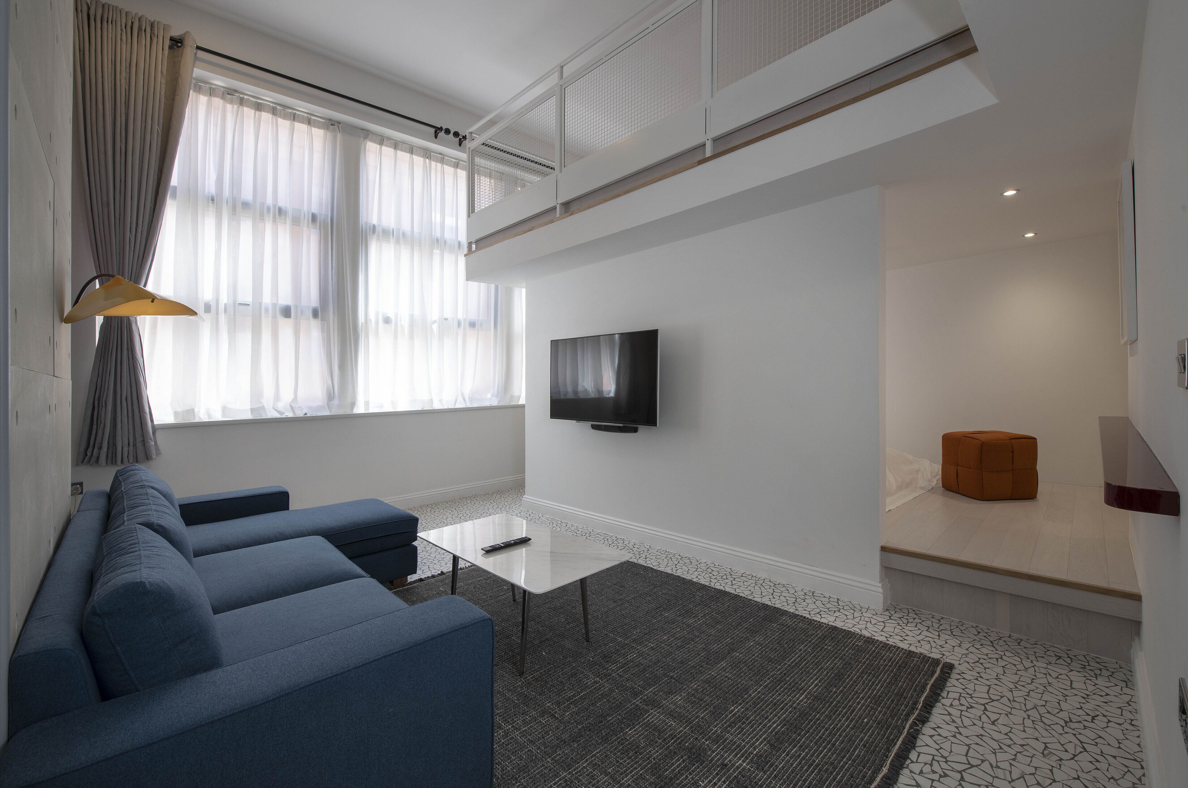 A modern living room with a sofa set, a flat-screen TV, and a small table.