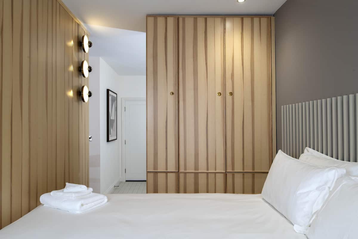 A hotel room with a bed, a wardrobe, and a mirror.