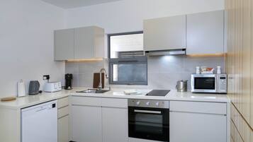 A modern kitchen with white cabinetry, a built-in oven, a microwave, and a dishwasher.