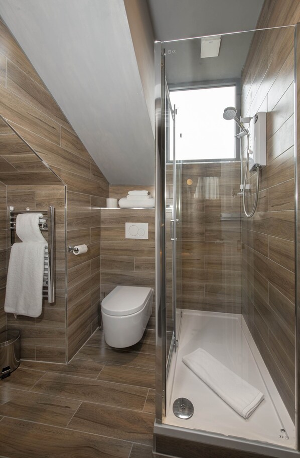 A modern bathroom with a glass shower enclosure, a toilet, and a towel rack.