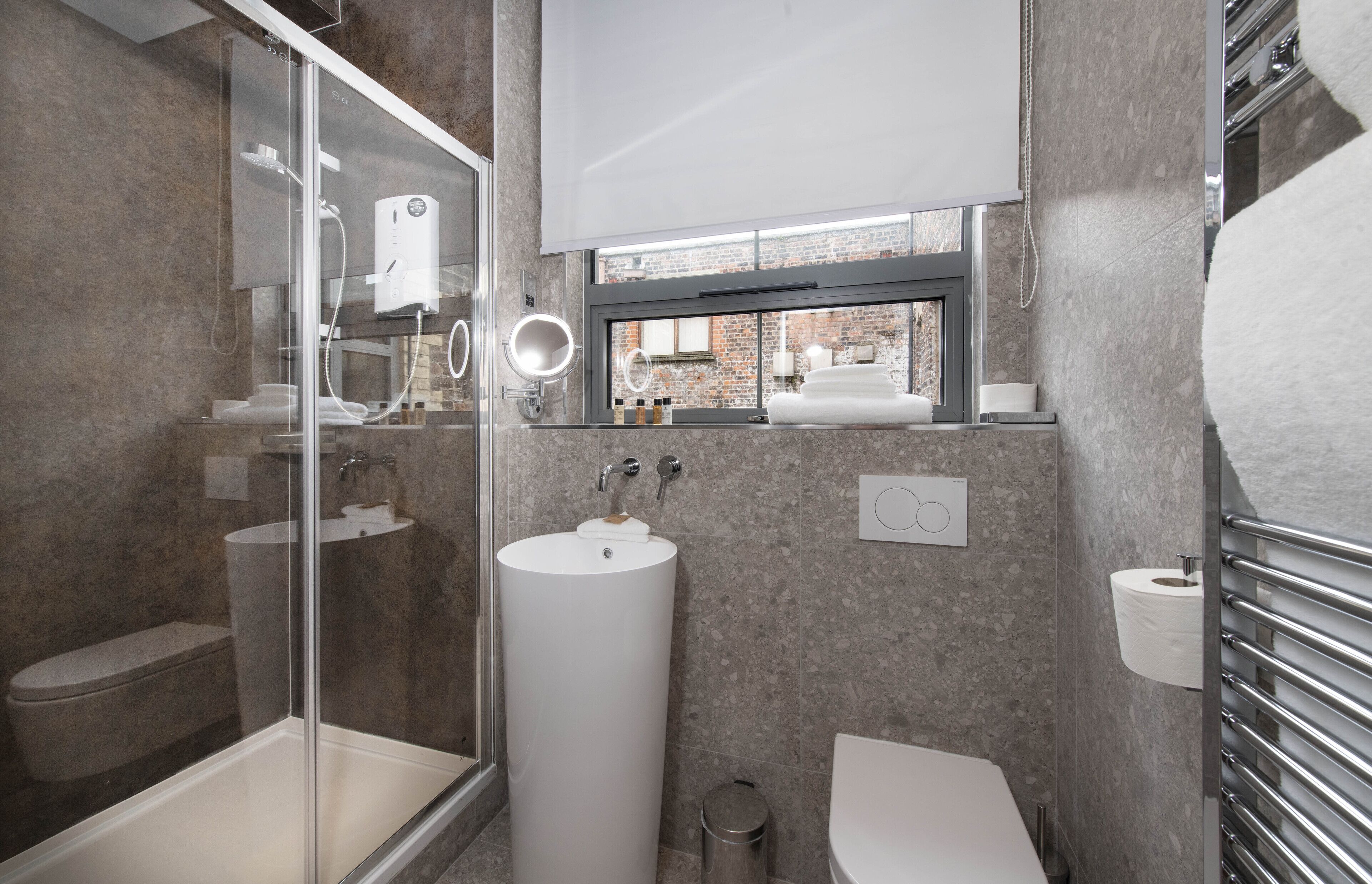 Un baño moderno con cabina de ducha de vidrio, lavamanos independiente y un inodoro.