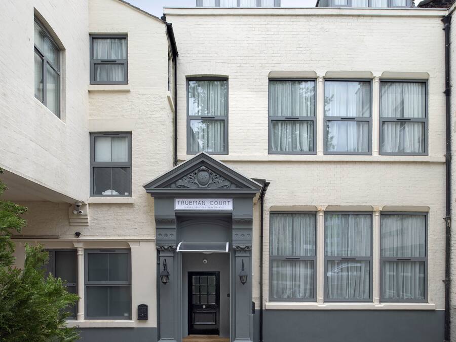 A building with a sign reading "TRUEMAN COURT LUXURY APARTMENTS."