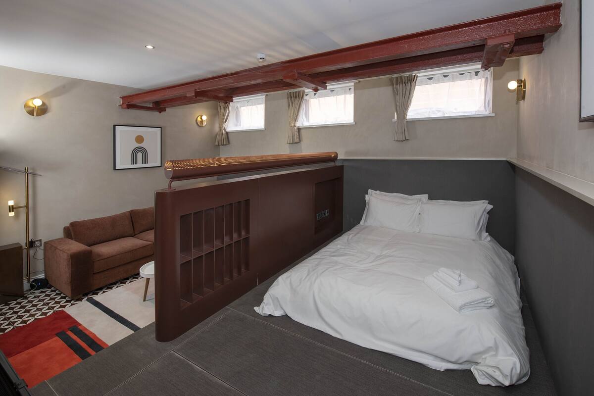 A bedroom with a bed, a sofa, a desk, and a picture on the wall.
