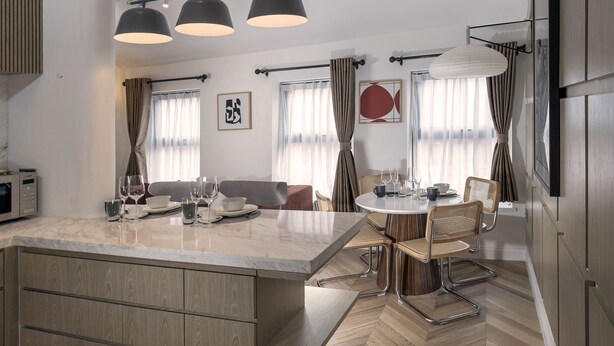 A modern kitchen with a large island, wooden cabinets, and a herringbone floor pattern. - Trueman Court Luxury Serviced Apartments (Liverpool)