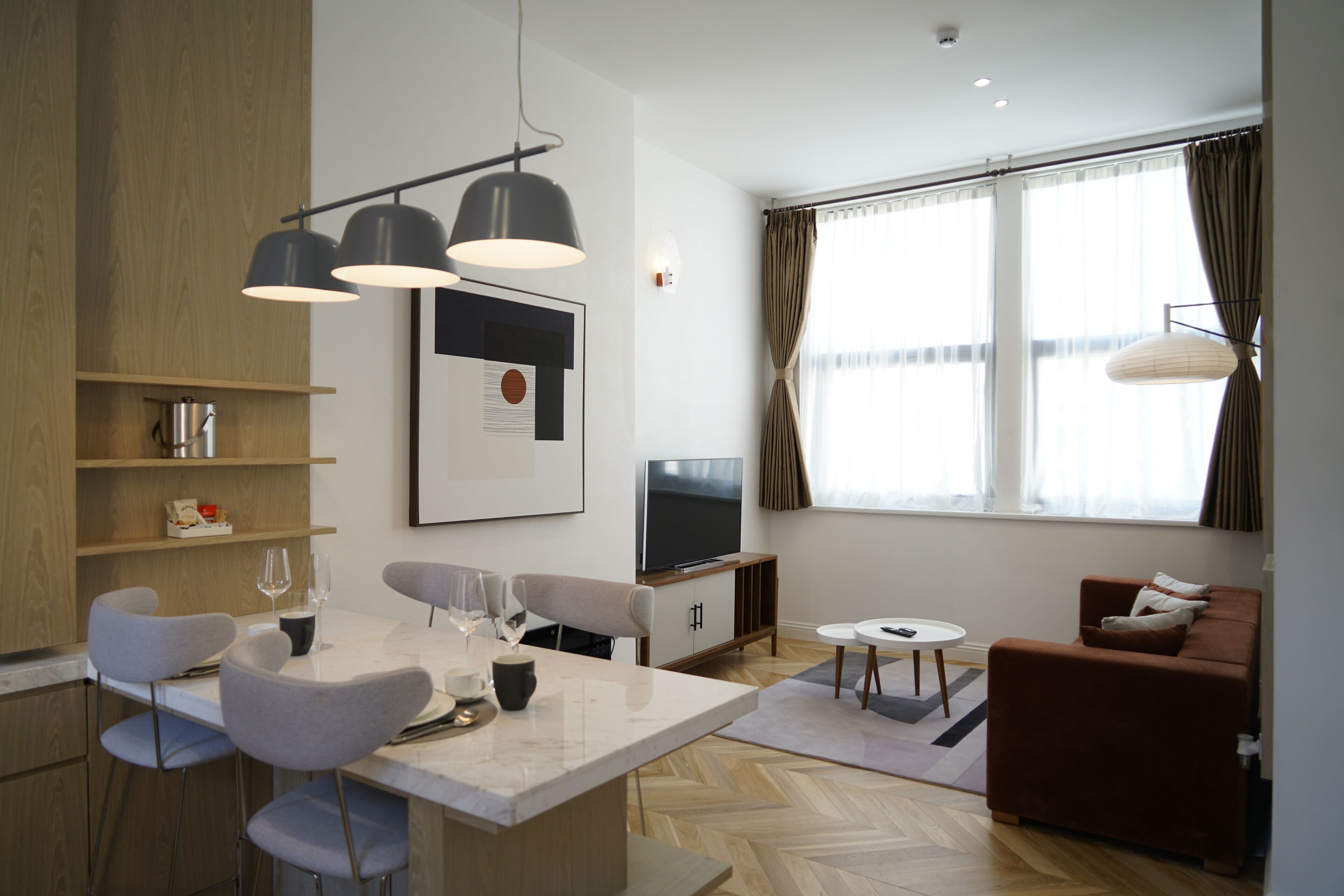 A modern living room with a sofa, a TV, and a dining area with chairs and a table.