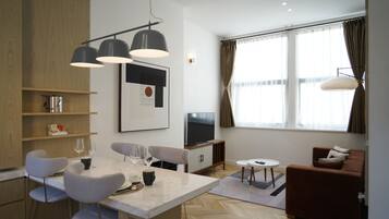 A modern living room with a sofa, a TV, and a dining area with chairs and a table.