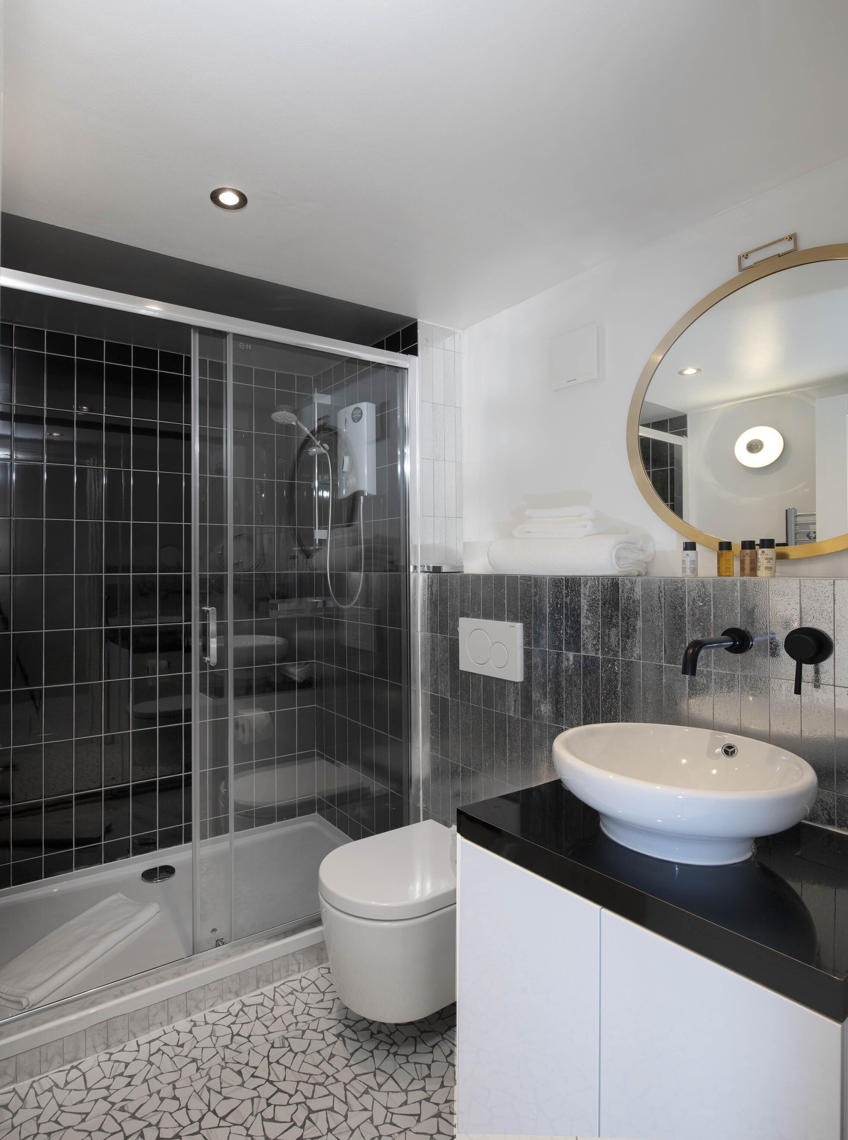 A modern bathroom with a glass-enclosed shower, a white sink, and a large mirror.