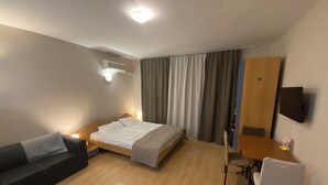 A hotel room with a bed, a desk, a chair, a TV, and a sofa. - Studio - Sleeps 4 & Access to Pools (Sunny Beach)