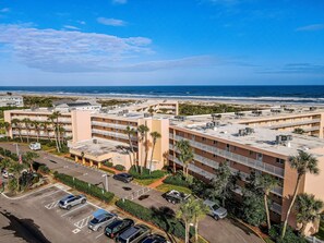 Un hôtel à plusieurs étages doté de balcons, d’un parking et offrant une vue sur la plage.