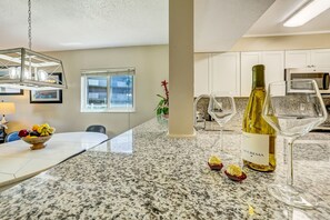 A kitchen with granite countertops, a wine bottle, and two wine glasses. - SunLounger|3BR/2BA Beachfront Retreat (Saint Augustine Beach)