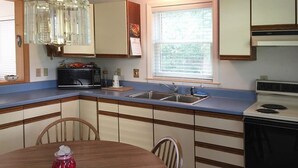 A kitchen with a blue countertop, a sink, a microwave, and a stove.