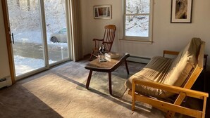 A living room with a sofa, a wooden table, a chair, and a ceiling fan.
