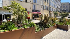 A courtyard with planters, a building with a 'farine chocolat' sign, and a clear blue sky. - Charming Mas in the countryside, near the village of Lambesc, large garden, (Lambesc)