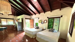 A room with two beds, a kitchenette, and a dining area.