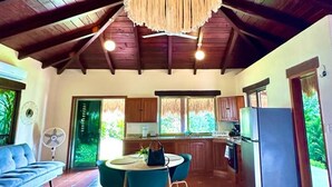A spacious kitchen with a dining area, wooden ceiling beams, and a large hanging light fixture.